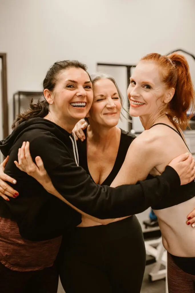 Three women standing in a circle with arms round each other