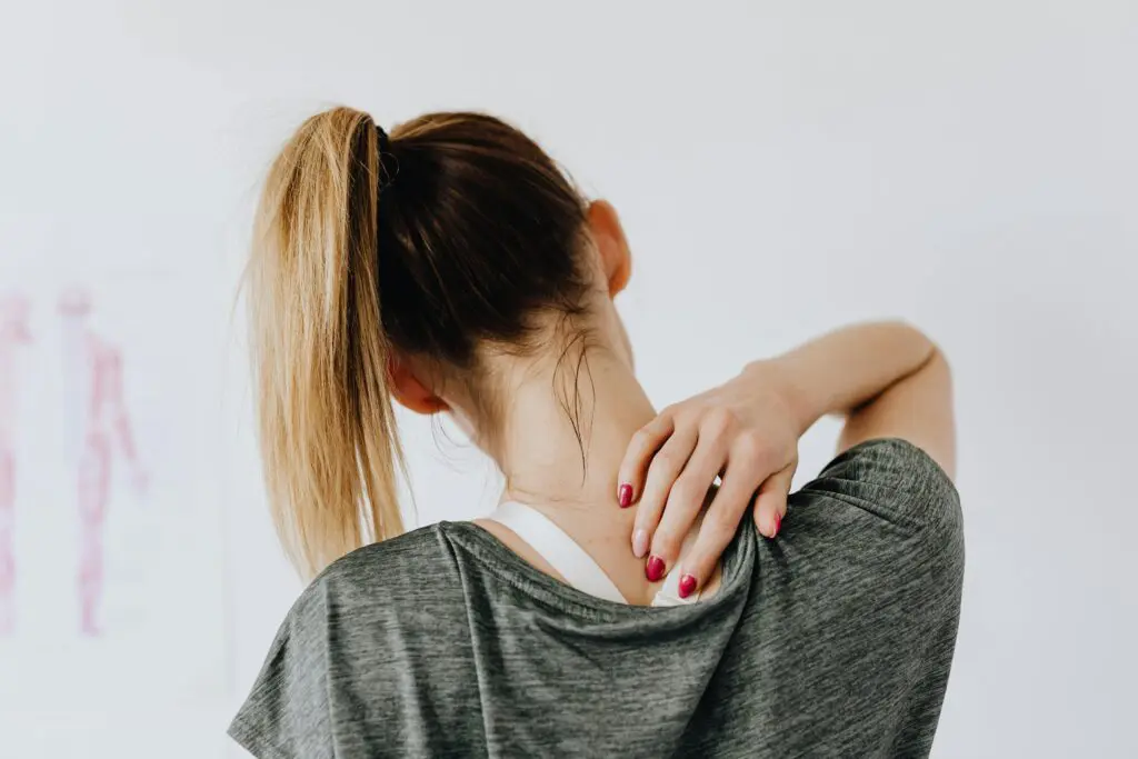Woman with her hand on the back of her shoulder